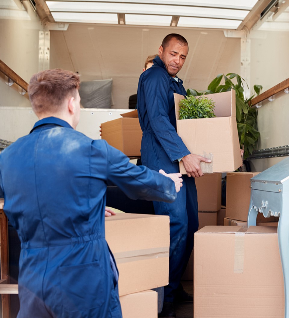two men in blue uniforms moving boxes in an office